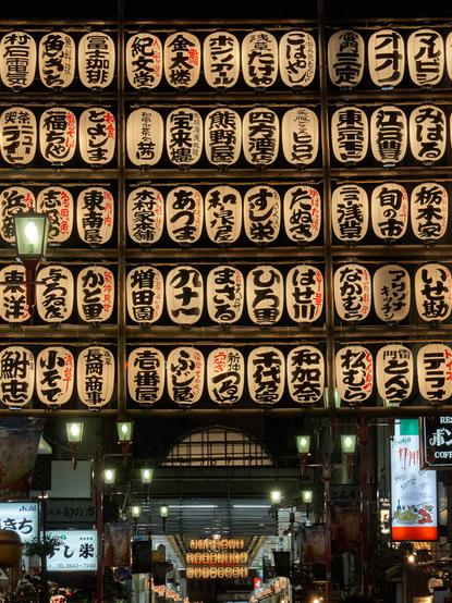 Paper lanterns glow in the evening, at the entrance to a classic shopping street (shotengai) in Asakusa.