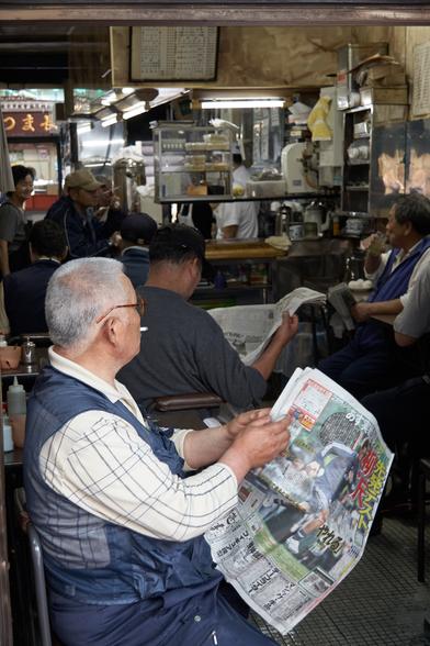 Fishmongers take a well deserved break after the early morning rush at Tsujii market, reading their newspapers in a run down restaurant.