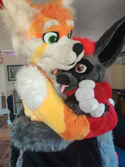 Fursuit photo of Dawn panda and Kofi bat giving each other a big hug