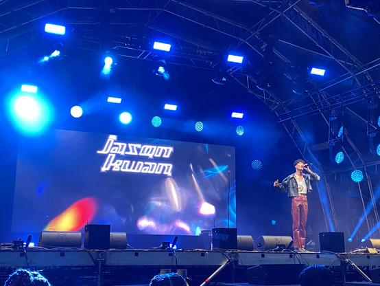 Jason Kwan sings on an illuminated stage with blue lighting.