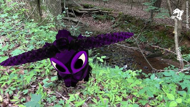 A black and purple dot with the horns chaos trait Rampage Drive, discovered by me. It is sitting in some wild plants with a creek in the background.