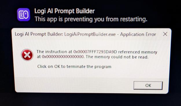 Photo of a computer monitor with an icon and the title "Logi AI Prompt Builder. This app is preventing you from restarting." and an error box saying "Logi AI Prompt Builder. Application Error. Click on OK to terminate the program."