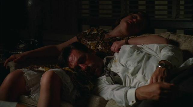 A man sleeping on a woman’s lap, who is also snoozing on a couch