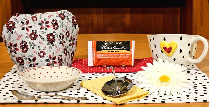 A tea tableau celebrating rainy days, with lots of raindrops and a tiny, shiny chrome umbrella. The tea is Constant Comment from Bigelow.