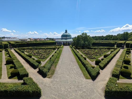 Foto vom mittig auf das Pavillon, wege gehen symmetrisch ab und trennen die Blumenbeete