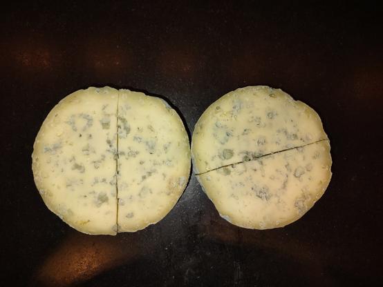 a wheel of homemade blue cheese, cut open so expose the veining.