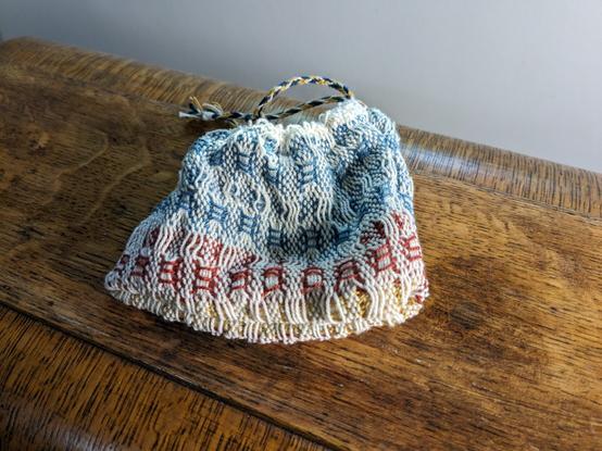 Handwoven drawstring pouch cinched up with more of the finger loop braided drawstring showing.