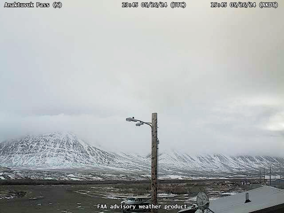 Webcam image looking south from the Anaktuvuk Pass airport with low clouds on the mountains and a fresh accumulation of snow just above elevation of town.