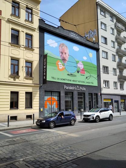 Buiding of Paralelni Polis with poster with Peppa the Pig and some dude's face pasted on Peppa's father. There's text "Tell us something about bitcoin, daddy pig".