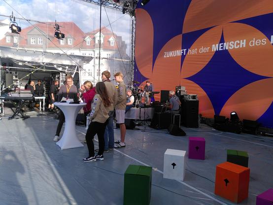 Die Katholikentagsbühne auf dem Erfurter Domplatz mit Pfadfinder an einem weißen Stehtisch.