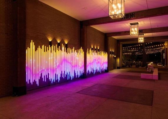 A large-scale light installation on a wall at a pedestrian underpass.
