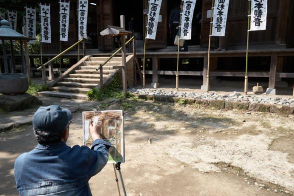 A watercolor artist quickly sketches out a painting of the staircase into an old temple building in Sugimotodera.