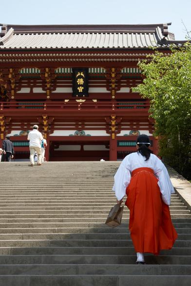A part time priestess (and probably a full time school student) walks the steps up to the main shrine.