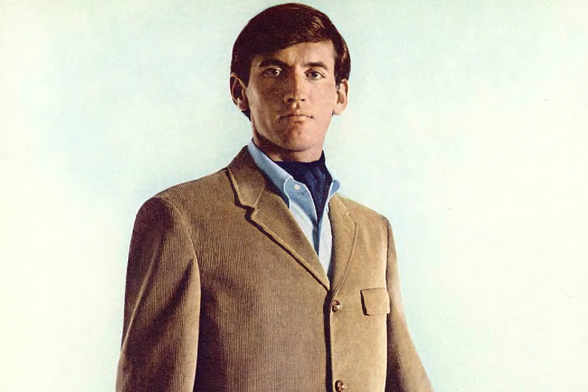 1966 The Classic Gentleman

The image features a man dressed in a classic, mid-20th-century business suit.
He is standing with confidence and has his hands casually tucked into the front pockets of his suit pants.
His attire includes a light brown blazer, a dark shirt, a tie, and a pocket square visible at the neckline.
The man's expression is neutral, and he appears to be looking directly ahead.
The background is a plain, light color, which contrasts with his suit and helps him stand out as the central figure in the image.