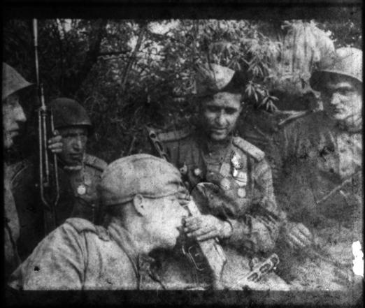 A black and white frame of a relaxed group of soldiers in uniform
