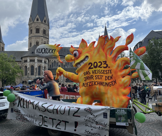 Wagen mit Feuerfigur, die die Öffentlichkeit aufmerksam macht, Aufschrift: 2023 das heisseste Jahr seit den Aufzeichnungen