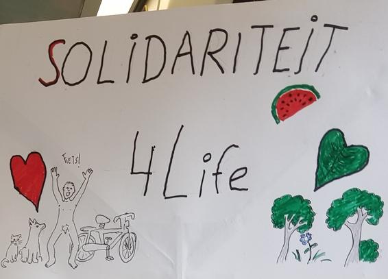 Protest sign that says "solidariteit 4 life"
Has a red and green heart left and right(green one was intended to look like a leaf) there is also a melon slice.
Under the red heart is a cat and dog and a naked man chearfully saying "fiets!" and a bike.
Under the green heart there are some trees, a flower