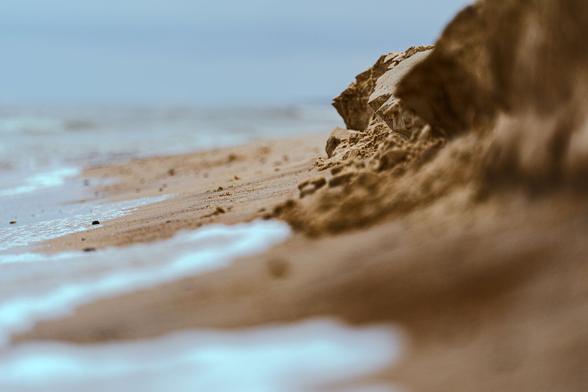 Tiny sea waves erroding the sand captured in a very shallow depth of field