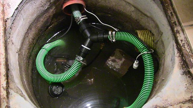 Blick in die Drainagegrube: Zwei Pumpen gekoppelt mit grünem Druckschlauch