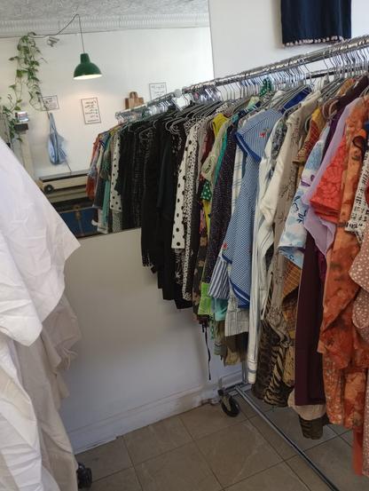 a rack of fem tops in front of a mirror in a shop
