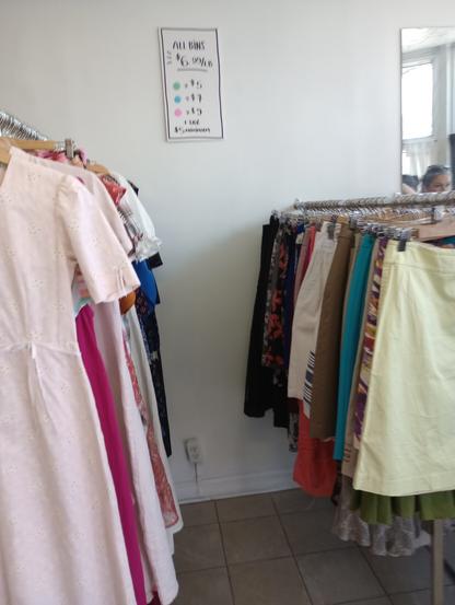 a rack of skirts and one of dresses in front of a pricing sign on the wall that says: all bins $6.99/lb, green dot tags are $5, blue are $7 and pink $9 + tax $5 minimum