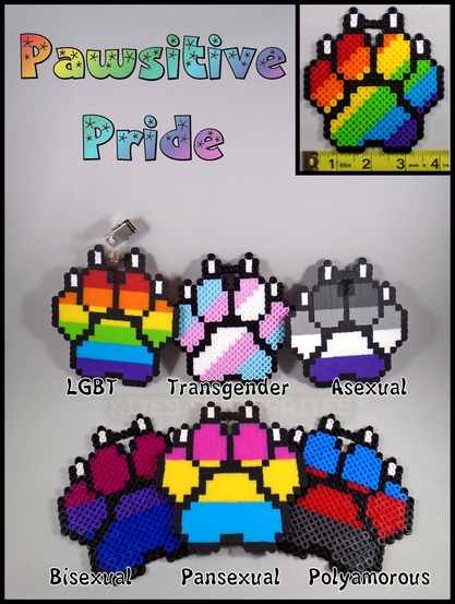 a photo of a variety of pawprint shaped badges with badge-clips attached. each pawprint badge is made out of small plastic melty-beads (Perler, Hama, etc). of the pawprint designs, each is colored with different pride flag colors. there is a rainbow colored pawprint, a blue-pink-white one for transgender, black-grey-white-and-purple for asexual. the bisexual pawprint is magenta, purple, and blue. pansexual is pink, yellow, and blue. and polyamory is blue, red, and black.
