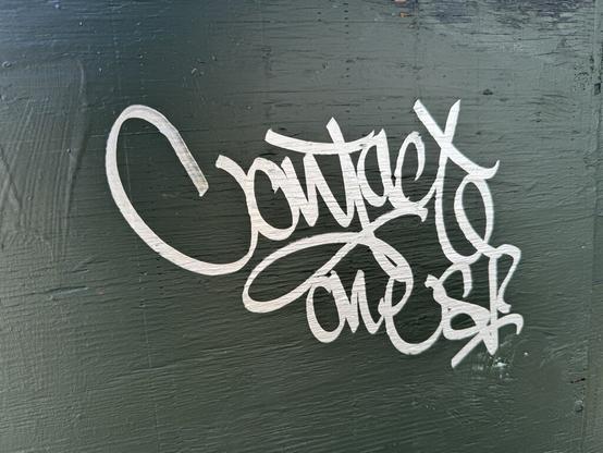 "Contact One SF" written on a green USPS mail box. The writing is done with a silver ink and is very smooth.