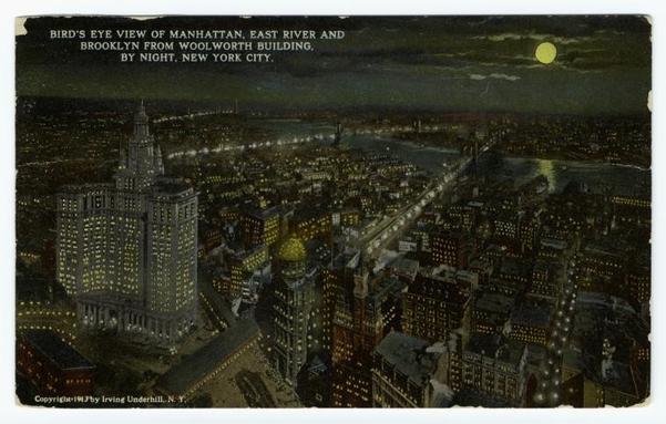 The image is a vintage postcard depicting a cityscape at night. In the foreground, there's a text that reads "Bird's eye view of Manhattan East and West Rivers and New York City by night." Below this description, the name "New York City" is prominently displayed. The scene features various buildings illuminated under the night sky, with the silhouette of the Statue of Liberty visible in the background. There's a street lamp providing additional lighting to the scene. The overall atmosphere suggests that this postcard captures an iconic view of one of the world's most famous cities, New York City, during its early years.