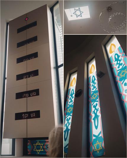 Dreigeteilten Bild. Links hochkant ein großer, moderner Torah-Schrein mit Aussparungen, durch die man hebräische Schrift lesen kann. Rechts oben eine Aufnahme der Decke - links ein Davidstern in einem rechteckigen Dachfenster, rechts ein moderner Kronleuchter. Rechts unten hochkant drei schmale Fenster, sie sind mit grün-blauen Ornamenten versehen, unten und in der Mitte gelbe Davidsterne, oben drauf eine Kerzenflamme.
Die insgesamt sieben Fenster ergeben so (zufälligerweise, die Beklebung wurde wegen zu starker Sonneneinstrahlung nachträglich aufgebracht) eine Menorah.
