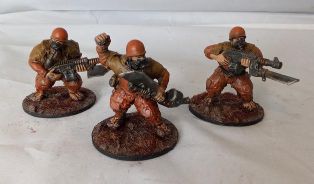 Three coverted Ogryns in orange jumpsuits, gasmasks, and rags.