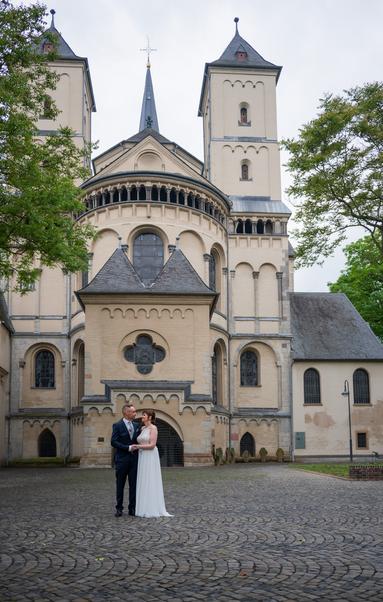 Ein Foto eines Brautpaars vor der Abteikirche in Brauweiler. Das Paar ist recht klein unten links zu sehen, eine Weitwinkelaufnahme.