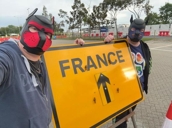two human pups standing next to a UK diversion street sign pointing to "France"