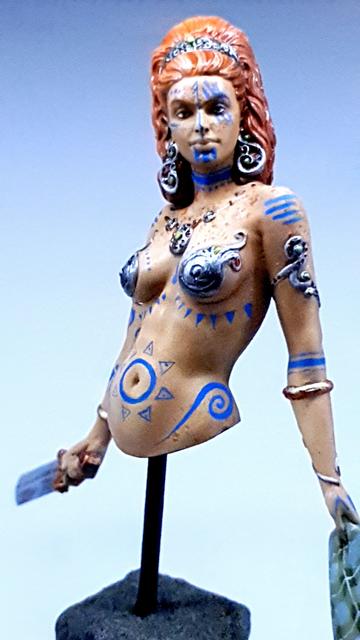 Photo of just the bust figurine (not the megalith or the grass), with her looking straight down the camera, looking very... Resolved in a violent course of action.