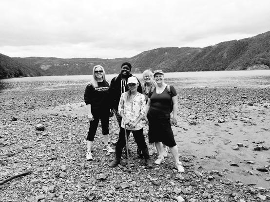 Me & 4 female friends at rocky beach, with ocean & mountain range behind us.