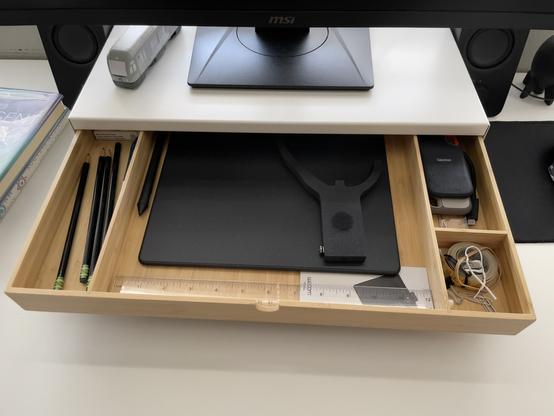 Compartmentalized bamboo drawer of the IKEA Elloven storing pencils and various gizmos