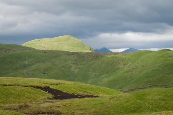green mountains in light and shadow with dark clouds