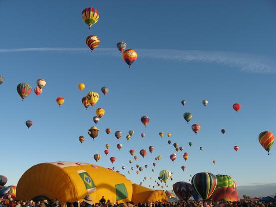 A picture of many hot air balloons in the sky and launching at the Albuquerque International Balloon Fiesta.