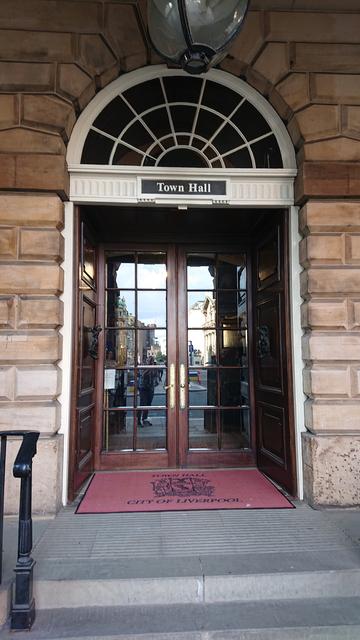 An arched doorway into a stone building.  Above the door is a sign reading "Town Hall" and the doormat features the coat of arms and text "City of Liverpool"