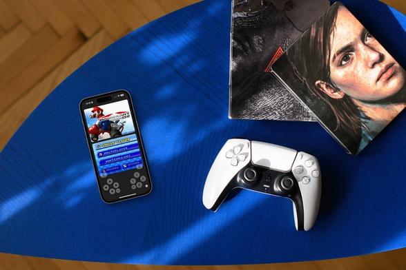 Emulator Folium mit Nintendo DS-Spiel auf einem iPhone, daneben ein PS5-Controller und ein Konsolenspiel auf einer blauen Oberfläche.
