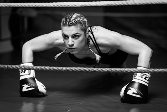 Kickboxerin, die mit Boxhandschuhen im Ring Liegestütz macht