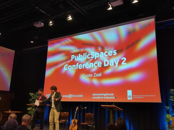 Roland Duong on stage on screen "PublicSpace Conference Day 2" 'Grote Zaal"