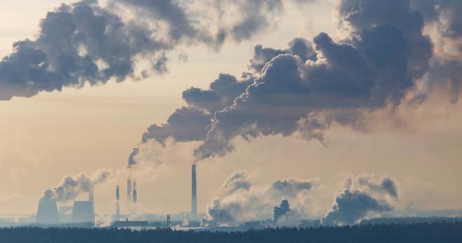 Industrieanlagen mit großen Rauchwolken, die in den Himmel aufsteigen.
