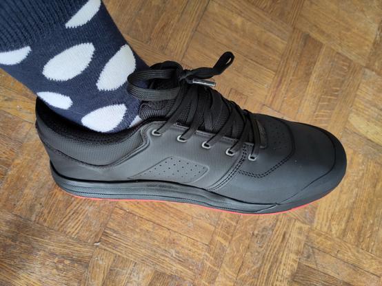 La chaussure sur mon pied avec des chaussettes bleues marine à pois blancs.