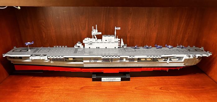1:300 scale model of the USS Enterprise CV-6 from the side on a wooden shelf.