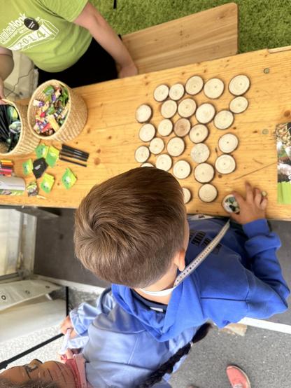 Ein Foto von oben fotografiert, das am #GemeinsamBuddeln-Stand aufgenommen wurde. Zu sehen ist ein Kind, das mit einem Baum-Memoryspiel spielt.