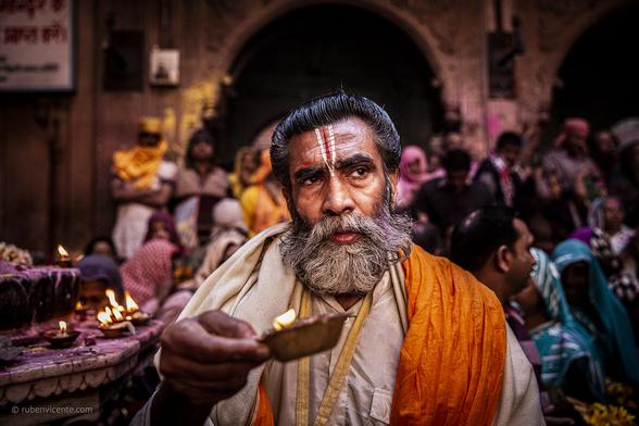 Man carrying a candle while attending Holi celebrations inside Bankey Bihari temple. Vrindavan, India