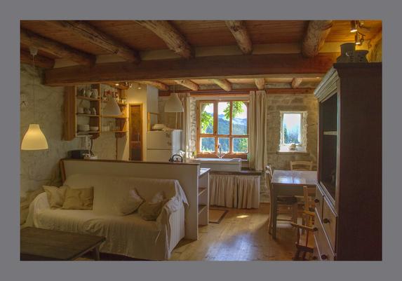 The interior of a stone house with wooden floor, beams, and ceiling and a light filled window