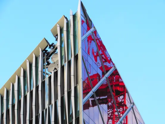 Red building crane, reflected in glass of building