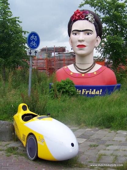 A several metres high bust of Frida Kahlo with my velomobile parked in front. This was in Assen a couple of years ago when Kahlo's work was exhibited in the museum, but since the exhibition closed she's for some reason taken up residence next to this cycle-path in an industrial area of Groningen.