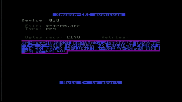 Screenshot of a Commodore 64 running the StrikeTerm terminal program and downloading a file via xmodem CRC. The current 218 byte buffer is displayed in PETSCII in the middle of the screen while transferring.